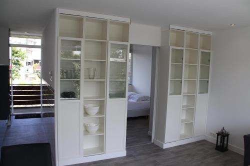 un soggiorno con mobili bianchi e un letto di Appartement De Zeester a Zandvoort