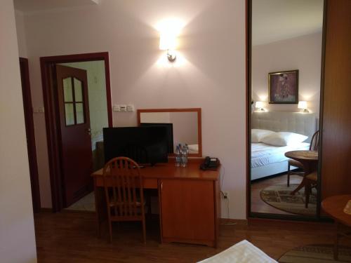 a room with a desk and a bed and a mirror at Hotel Bartis in Bartoszyce