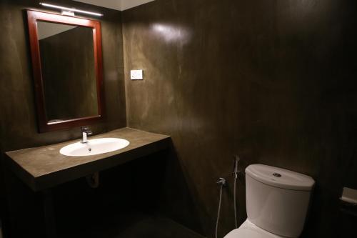 a bathroom with a sink and a toilet and a mirror at Cozy Sea view Inn in Hikkaduwa