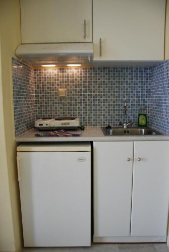 a kitchen with white cabinets and a sink at Koulas Pension - Red Lake in Agios Prokopios