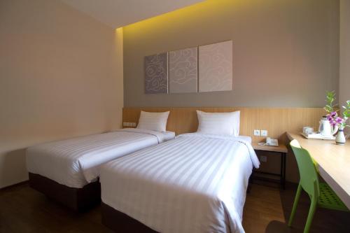 two beds sitting next to each other in a room at Vinotel Cirebon in Cirebon