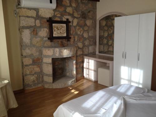 アンタルヤにあるミュンヘン ペンションの石造りの暖炉とベッド付きのベッドルーム1室