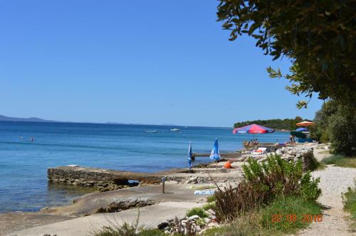 a beach with chairs and umbrellas on the water at Apartment PALATISA in Kožino