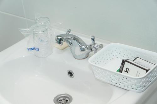a bathroom sink with a soap dispenser in a basket at Amfora in Palić