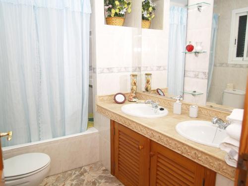 Un baño con dos lavabos, un inodoro y una ducha. en Villa López, en Santanyí
