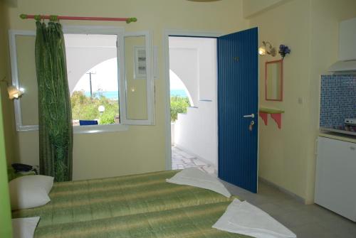 a room with a bed and a door with a window at Koulas Pension - Red Lake in Agios Prokopios