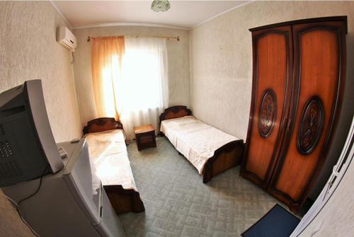 a bedroom with two beds and a tv and a window at Максим in Gelendzhik