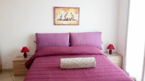 a bed with a purple comforter and two night stands at La trifula bianca apts. in Alba