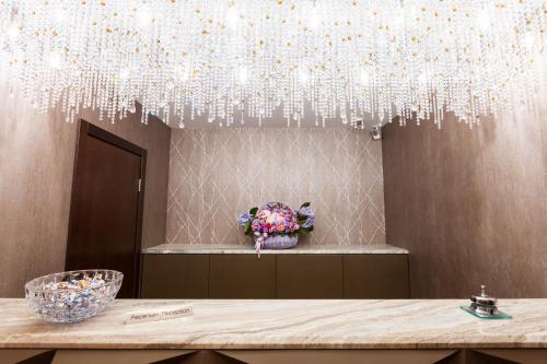 un tavolo con un vaso di fiori sotto un lampadario a braccio di Crystal Hotel a Kiev