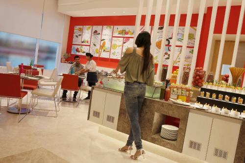 a woman standing at a counter in a restaurant at ibis Coimbatore City Centre - An Accor Brand in Coimbatore