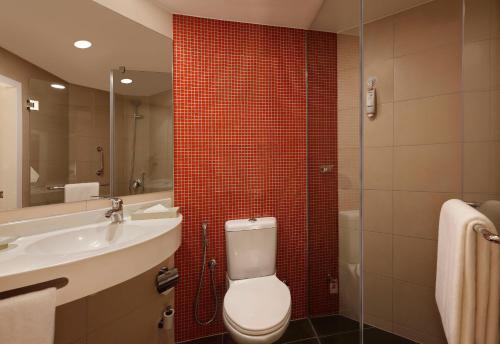 a bathroom with a toilet and a sink and a mirror at ibis Coimbatore City Centre - An Accor Brand in Coimbatore
