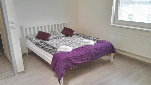 a bedroom with a bed with purple sheets and pillows at Alfa Panorama Brno in Brno