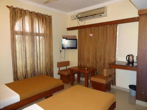 a room with two beds and a table and a television at Sheetal Residency in Bangalore
