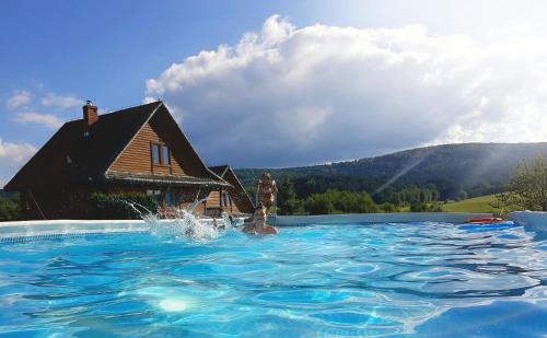 a person in a swimming pool in front of a house at Bieszczadzki Ośrodek Wypoczynkowo Konferencyjny DANFARM in Ustrzyki Dolne