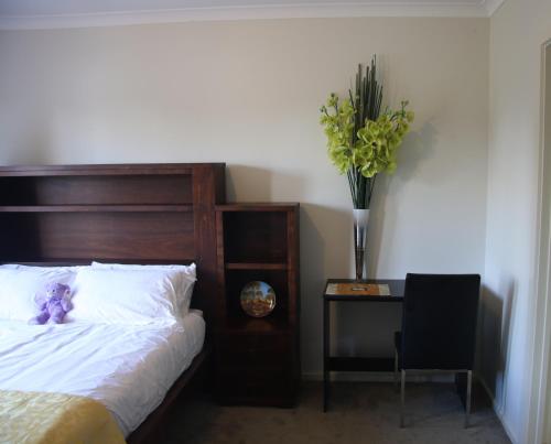 a bedroom with a bed and a table with a vase of flowers at Apple House in Tarneit