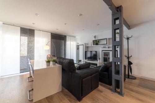 a living room with a black leather couch and a table at Apartamento Luis de Vargas in Huelva