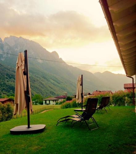 two chairs and umbrellas on a lawn with mountains in the background at Bianco Hotel in Primaluna