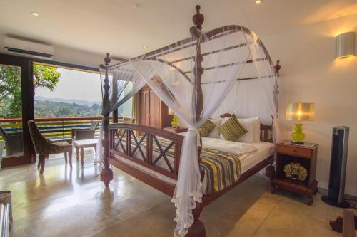 ein Schlafzimmer mit einem Himmelbett mit einem Tisch und Stühlen in der Unterkunft The Elephant Stables in Kandy