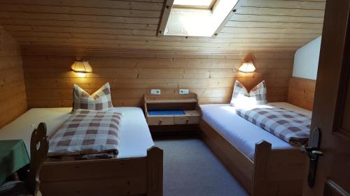 dwa łóżka w pokoju z drewnianymi ścianami w obiekcie Gasperlerhof w Neustift im Stubaital