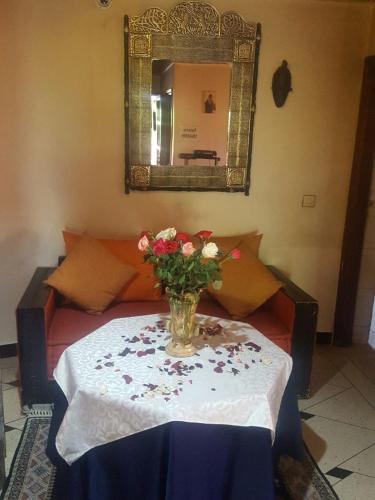a vase of flowers on a table with a mirror at Riad Villa Midelt in Midelt