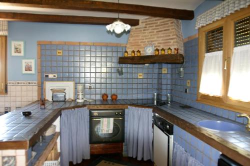 cocina con paredes de azulejos azules y fogones en Complejo Rural El Marañal, en Caspueñas