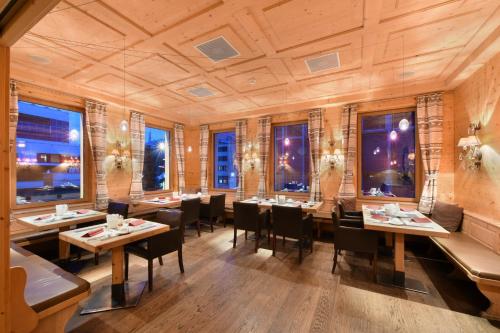 a restaurant with tables and chairs and windows at Hotel Piz St. Moritz in St. Moritz