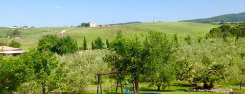 a green field with trees and a house on a hill at Il Girasole Terzuolo in Manciano