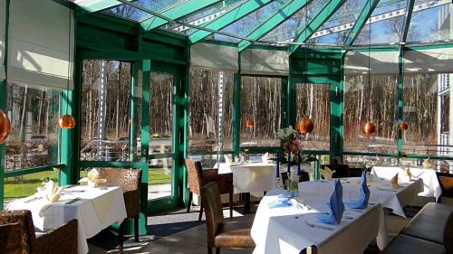 a restaurant with white tables and chairs and windows at Parkhotel IV Jahreszeiten Kühlungsborn in Kühlungsborn
