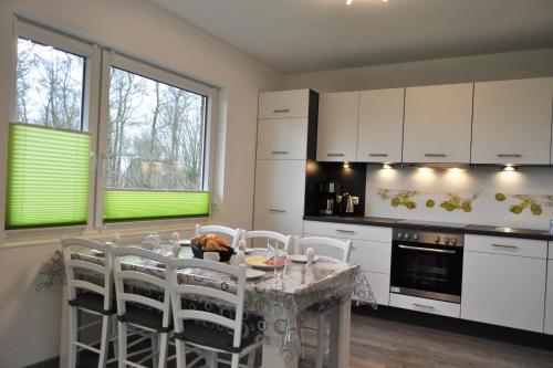 a kitchen with a table with white cabinets and white chairs at Dieken's Huus in Wangerland