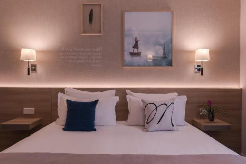 a bed with white pillows and a picture on the wall at Magda Champs Elysées in Paris