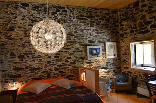 una camera da letto con una parete in pietra e un lampadario a braccio di Mesao Provesende a Provesende