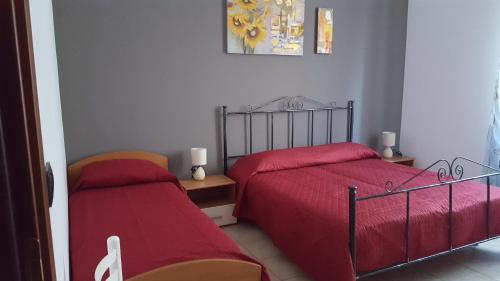 トラーパニにあるCasa Miceliの赤いシーツが備わるベッドルームのベッド2台
