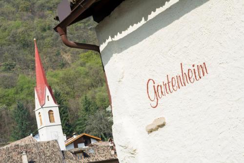 a sign on the side of a building with a church at Garni Gartenheim in Caldaro