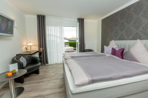ein Schlafzimmer mit einem großen Bett und einem Stuhl in der Unterkunft Landhotel Bartmann in Sendenhorst