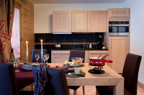 a kitchen and dining room with a table and chairs at CGH Résidences & Spas l'Orée des Neiges in Landry