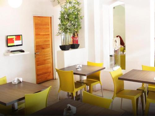 un comedor con mesas de madera y sillas amarillas en Hotel Las Terrazas Express, en Chillán
