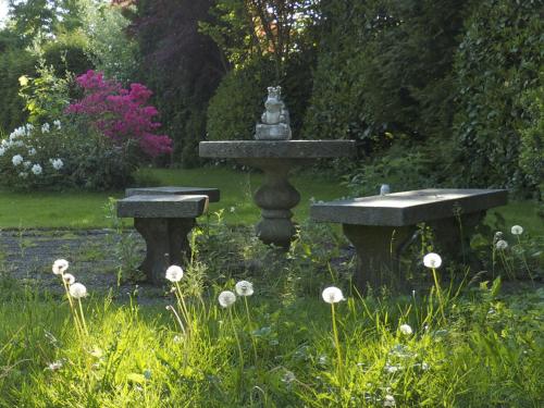 einen Brunnen in einem Garten mit zwei Steinbänken in der Unterkunft Villa Rana in Lindau