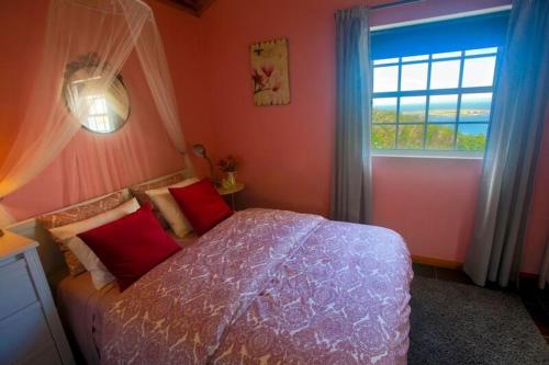 a bedroom with a bed with pink walls and a window at Recanto das Vigias "Vigia do Ilheu" in Topo