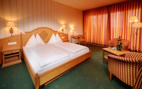 ein Hotelzimmer mit einem großen Bett und einem Stuhl in der Unterkunft Hotel Garni am Seggauberg in Leibnitz