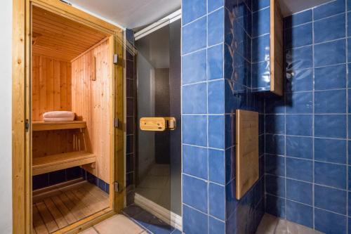 La salle de bains est pourvue de murs carrelés bleus et d'une douche. dans l'établissement Lodge aux Praz, à Chamonix-Mont-Blanc