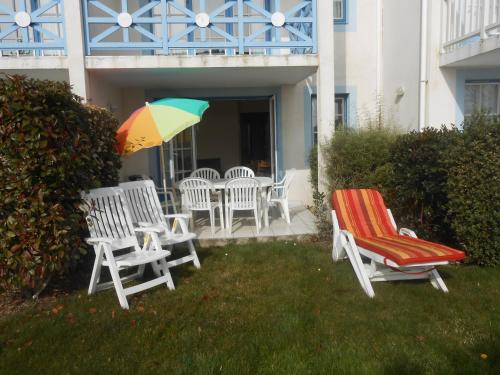 a group of chairs and a table with an umbrella at Port Bourgenay - Village P&V in Talmont