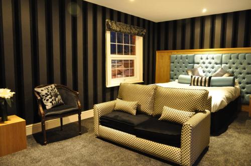 a bedroom with a bed and a chair at The Angel Inn Hotel in Pershore