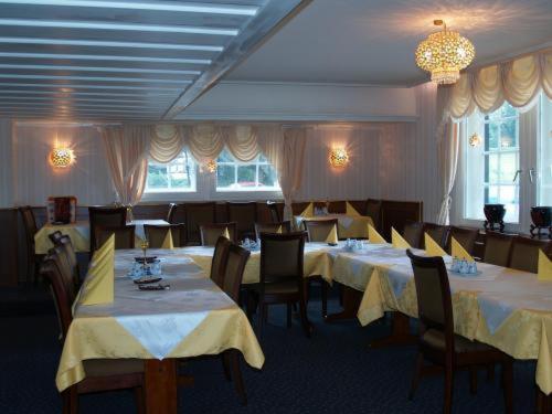 a dining room with tables and chairs with yellow table cloth at Hotel Royal Garden in Bad Iburg