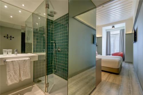 uma casa de banho com um chuveiro, um lavatório e uma cama em Vincci Baixa em Lisboa