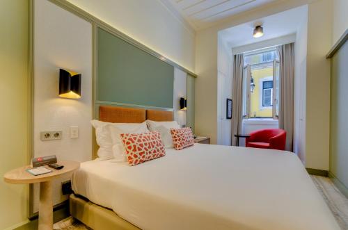 a hotel room with a large bed and a red chair at Vincci Baixa in Lisbon