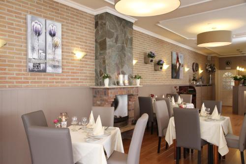 a dining room with tables and chairs and a fireplace at Hotel Kodde in Aagtekerke