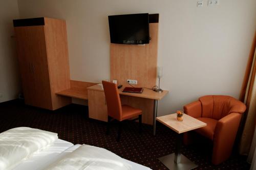 a hotel room with a bed and a chair and a desk at Hotel Am Freischütz in Hürth
