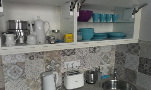 a kitchen counter with a sink and dishes on a shelf at Budanest Apartments in Budapest
