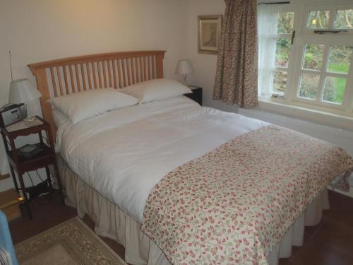 um quarto com uma cama grande e um edredão branco em Kipps Farm em Great Torrington