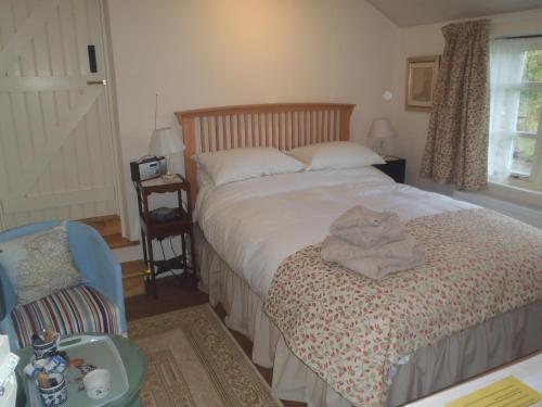 a bedroom with a bed and a chair and a window at Kipps Farm in Great Torrington